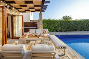 A poolside area with a table set for dining, lounge chairs, and a view of a swimming pool. - Hg06 Adjacent to Aphrodite Hills- Private Pool (Kouklia)