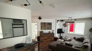 Un salon moderne avec un canapé, une table basse et un téléviseur. On y trouve également un meuble en bois et un miroir accroché au mur.
