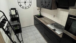 Une cuisine moderne avec deux horloges murales, un réfrigérateur en acier inoxydable et un four noir.