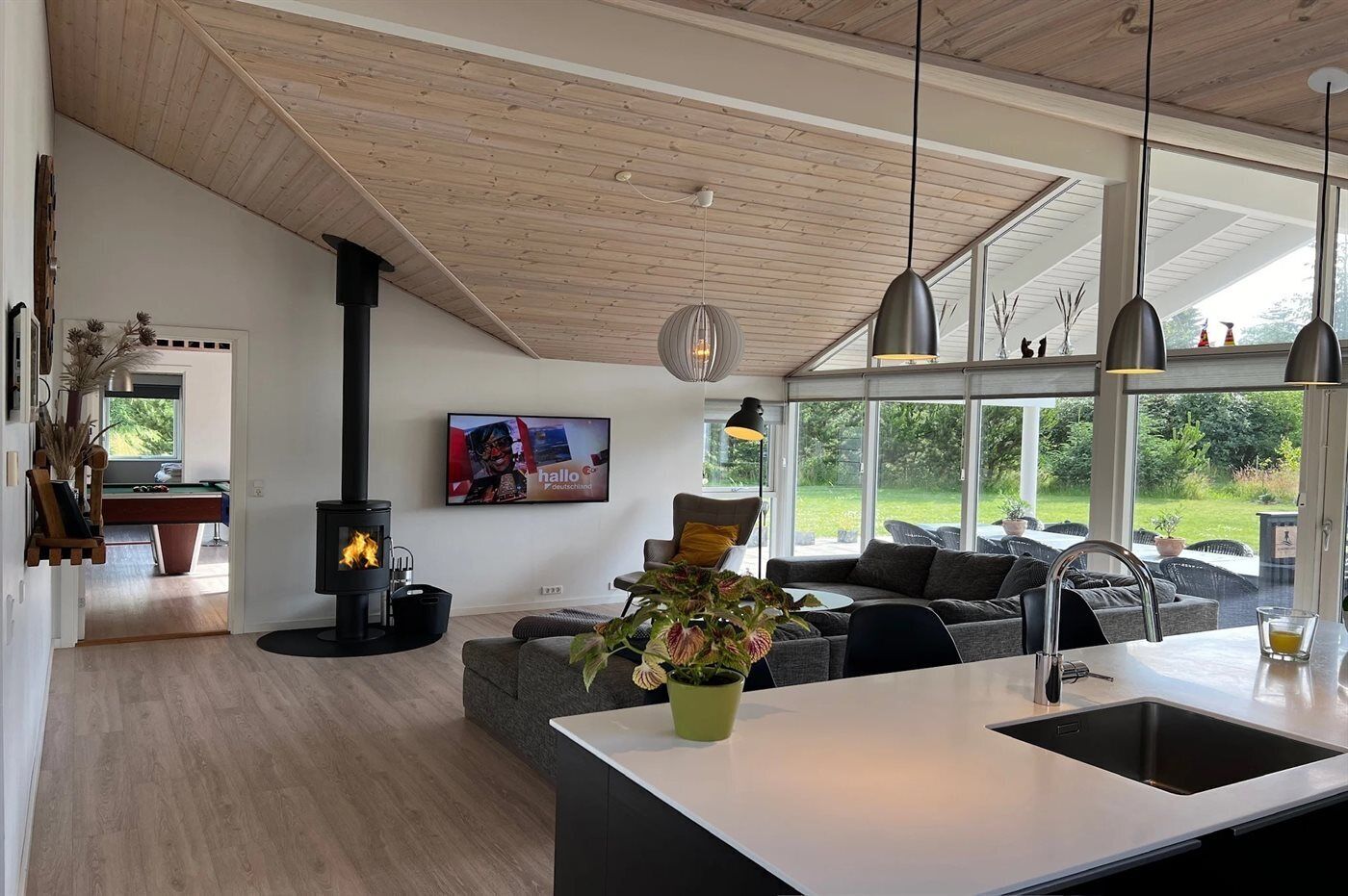 Uma sala de estar moderna com lareira, sofá, área de jantar e cozinha com uma janela grande.