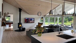 Un salon moderne doté d’une cheminée, d’un canapé, d’un coin repas et d’une cuisine avec une grande fenêtre.