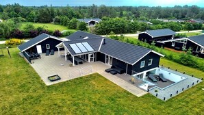 Une maison moderne dotée d’un grand patio, d’une piscine et d’une pelouse bien entretenue.