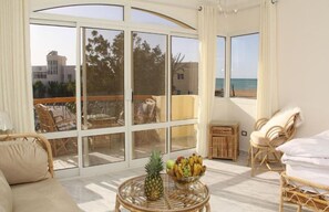 A spacious balcony with wicker furniture, a fruit bowl, and a view of the beach and buildings. - Villa Anna & Snake - Deluxe Queen Studio (Red Sea Governorate)