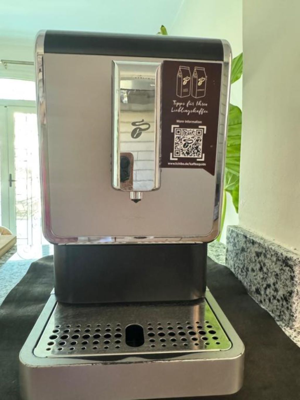 A coffee machine with a QR code and a website URL.