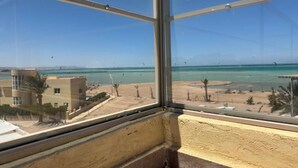 A view from a window overlooking a beach with clear skies and a few kites in the distance. - Villa Anna & Snake - One-Bedroom Apartment with Sea View and Terrace (Red Sea Governorate)