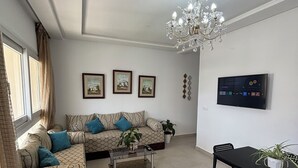 A living room with a sofa, coffee table, dining table, chairs, a TV, and a chandelier. - Apartment in a beautiful residence Mirador Golf 3, with 3 large swimming pools (Unknown)