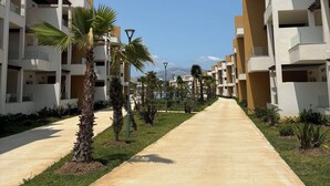 A modern resort with multiple-story buildings, a central pathway, and palm trees. - Apartment in a beautiful residence Mirador Golf 3, with 3 large swimming pools (Unknown)