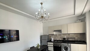 A modern kitchen with a dining area, a chandelier, a flat-screen TV, and a washing machine. - Apartment in a beautiful residence Mirador Golf 3, with 3 large swimming pools (Unknown)
