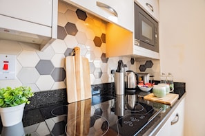 A modern kitchen with a black stovetop, a microwave, and a hexagonal tile backsplash. - Dublin Central Suites (Dublin)