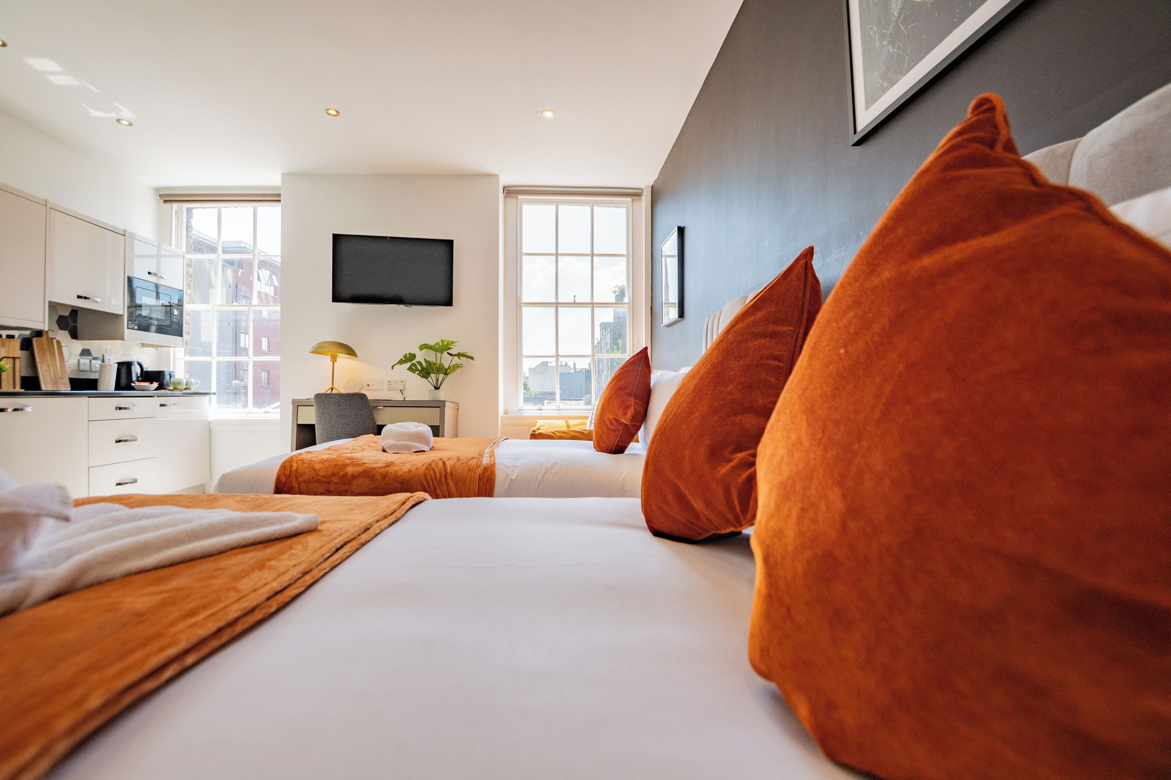 Une chambre d’hôtel avec un lit, un bureau, une chaise, une télévision et une fenêtre.