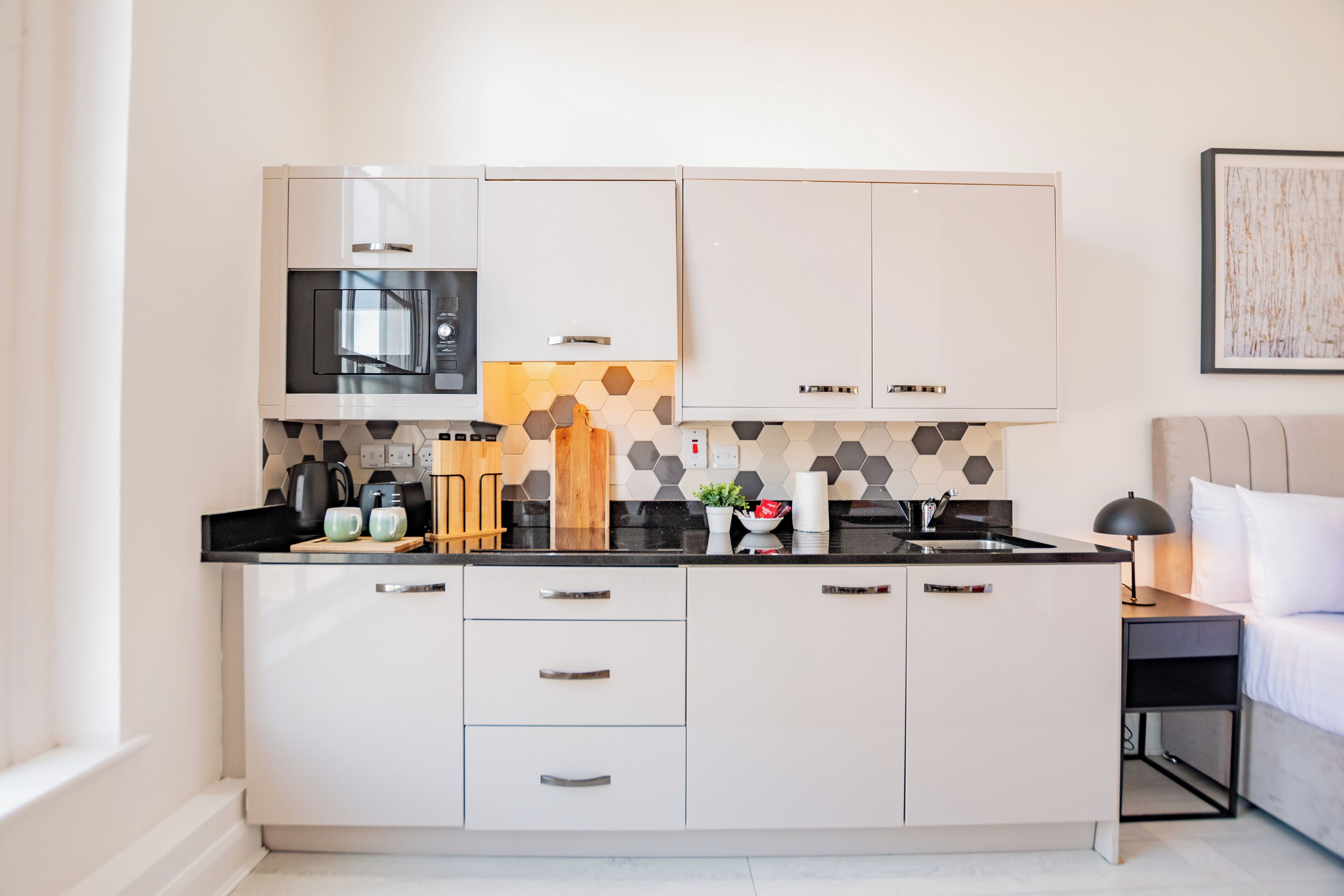 Uma cozinha moderna com armários brancos, micro-ondas e cafeteira.