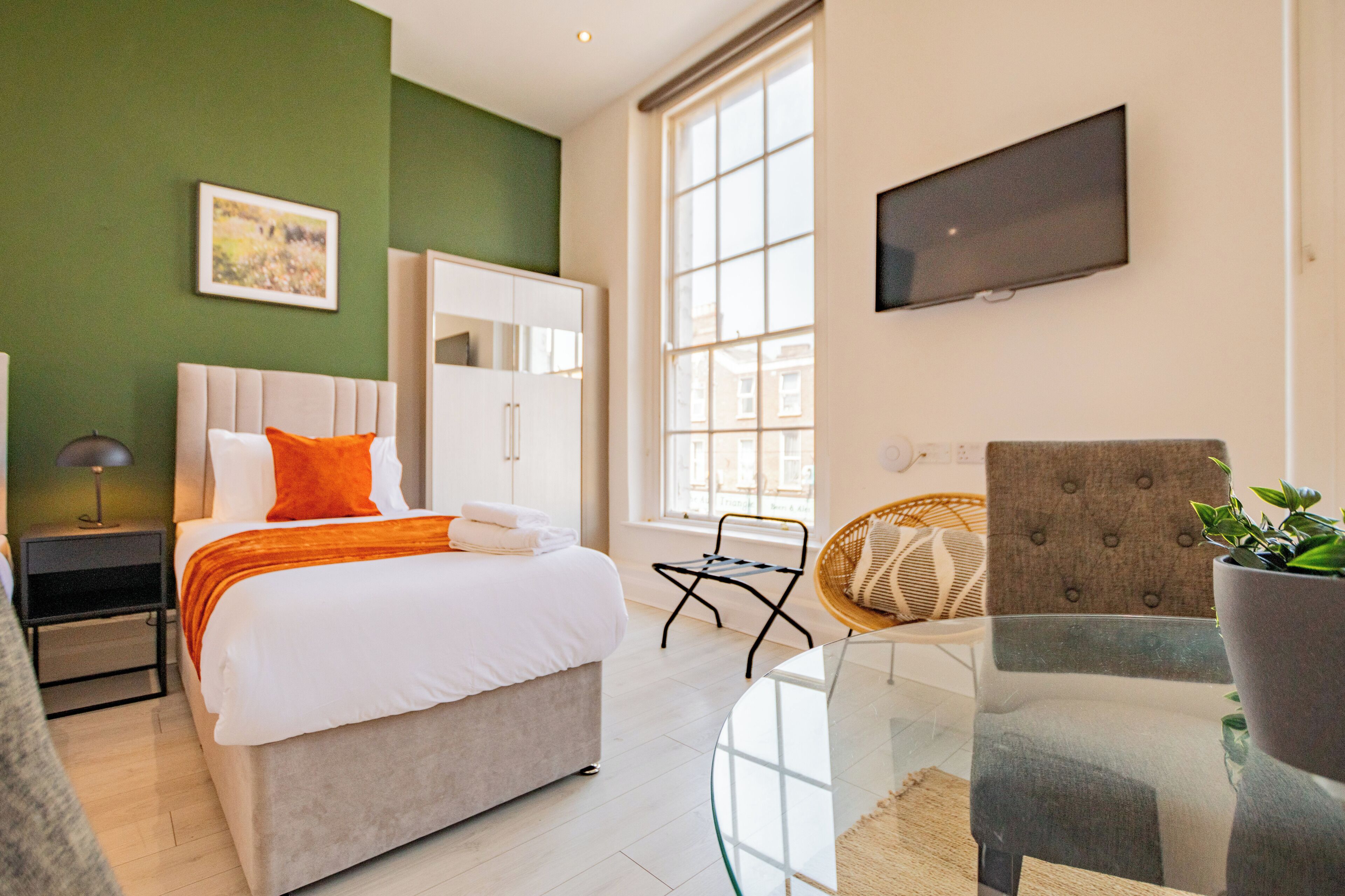 A modern hotel room with a bed, a television, a chair, and a window.