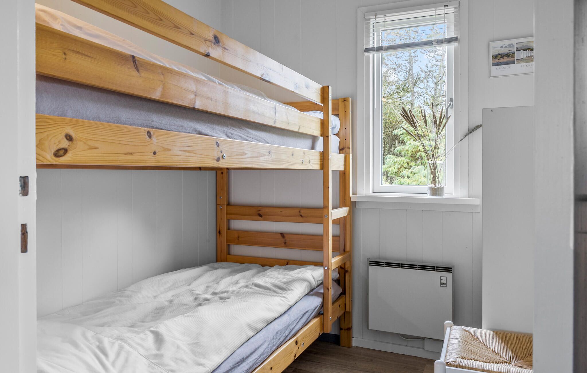Habitación con literas, ventana y radiador.