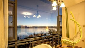Casa de banho com banheira, cadeira suspensa e vista para um lago e montanhas.