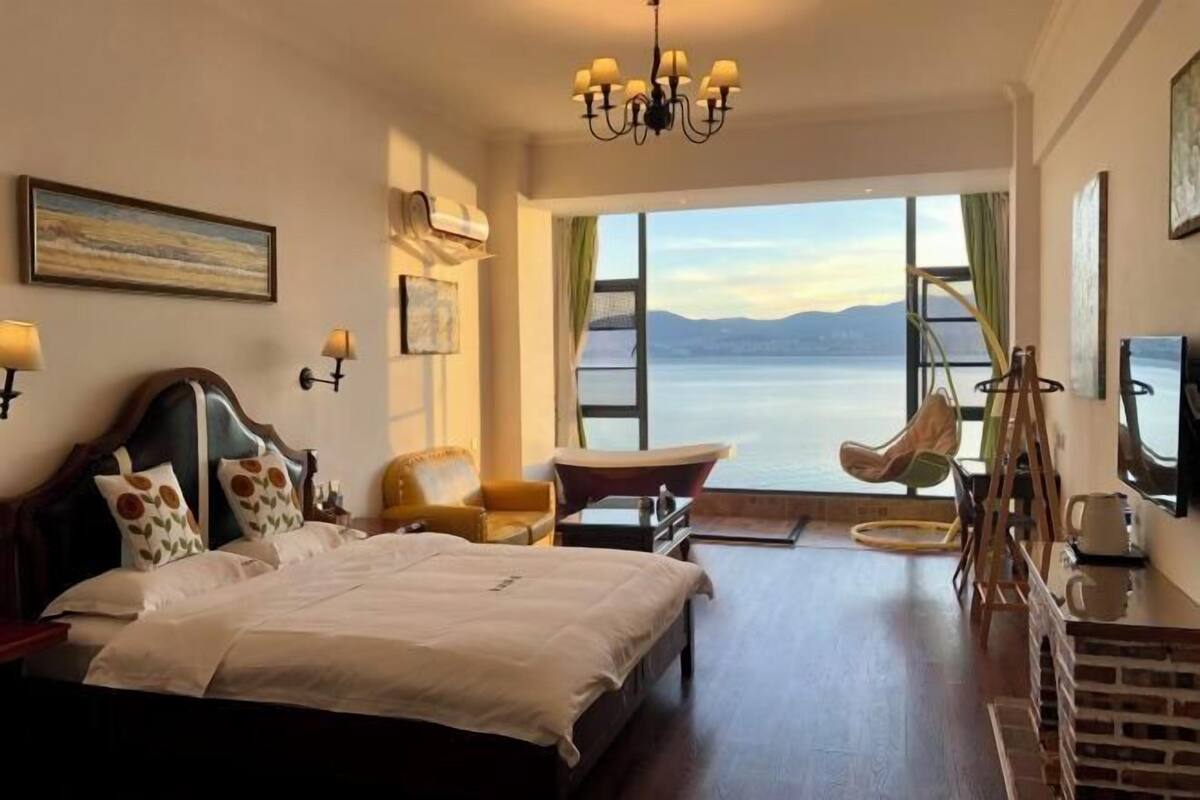 Une chambre d’hôtel avec un grand lit, une chaise, un bureau et une vue sur l’eau.