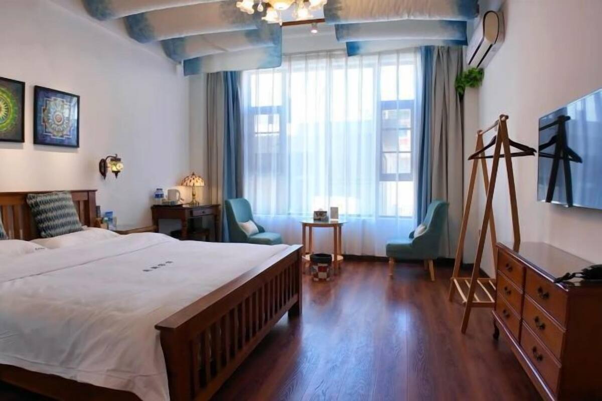 Une chambre d’hôtel avec un grand lit, deux chaises, une petite table et une commode.