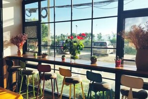 A café with a large window, several chairs, and potted plants. - Dali Zouzou Tingting Seaview Inn (Dali City)