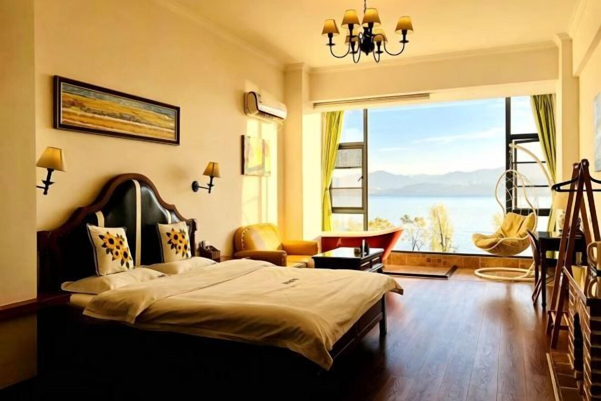 Habitación de hotel con una cama grande, vista al mar, una silla y una mesa.