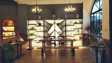 Un comedor con una mesa larga, sillas y una estantería con plantas.