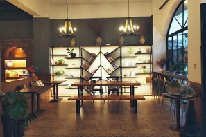 Un comedor con una mesa larga, sillas y una estantería con plantas.