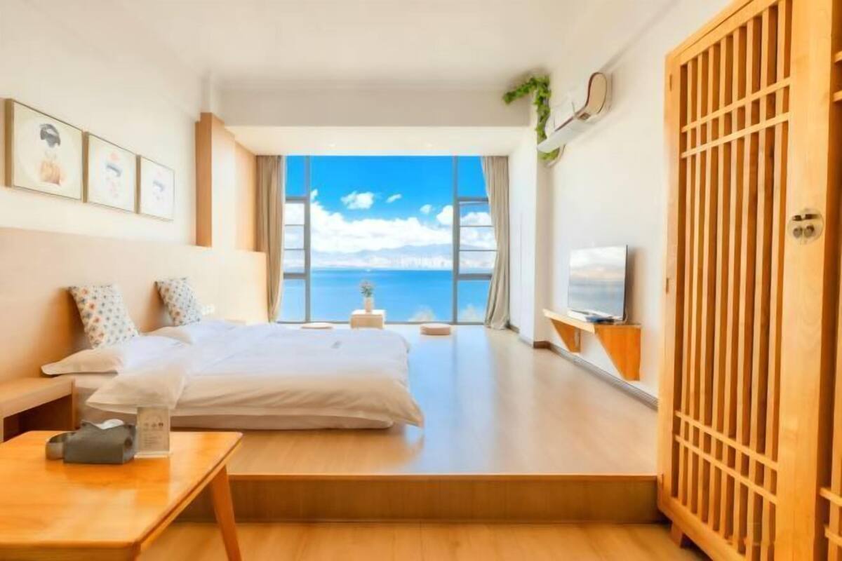 Une chambre d’hôtel moderne dotée d’un grand lit, d’un bureau, d’une télévision et offrant une vue sur la mer.