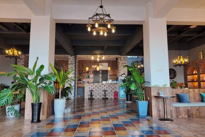 Un hall espacioso con suelo a cuadros, plantas en macetas y una zona de bar central.