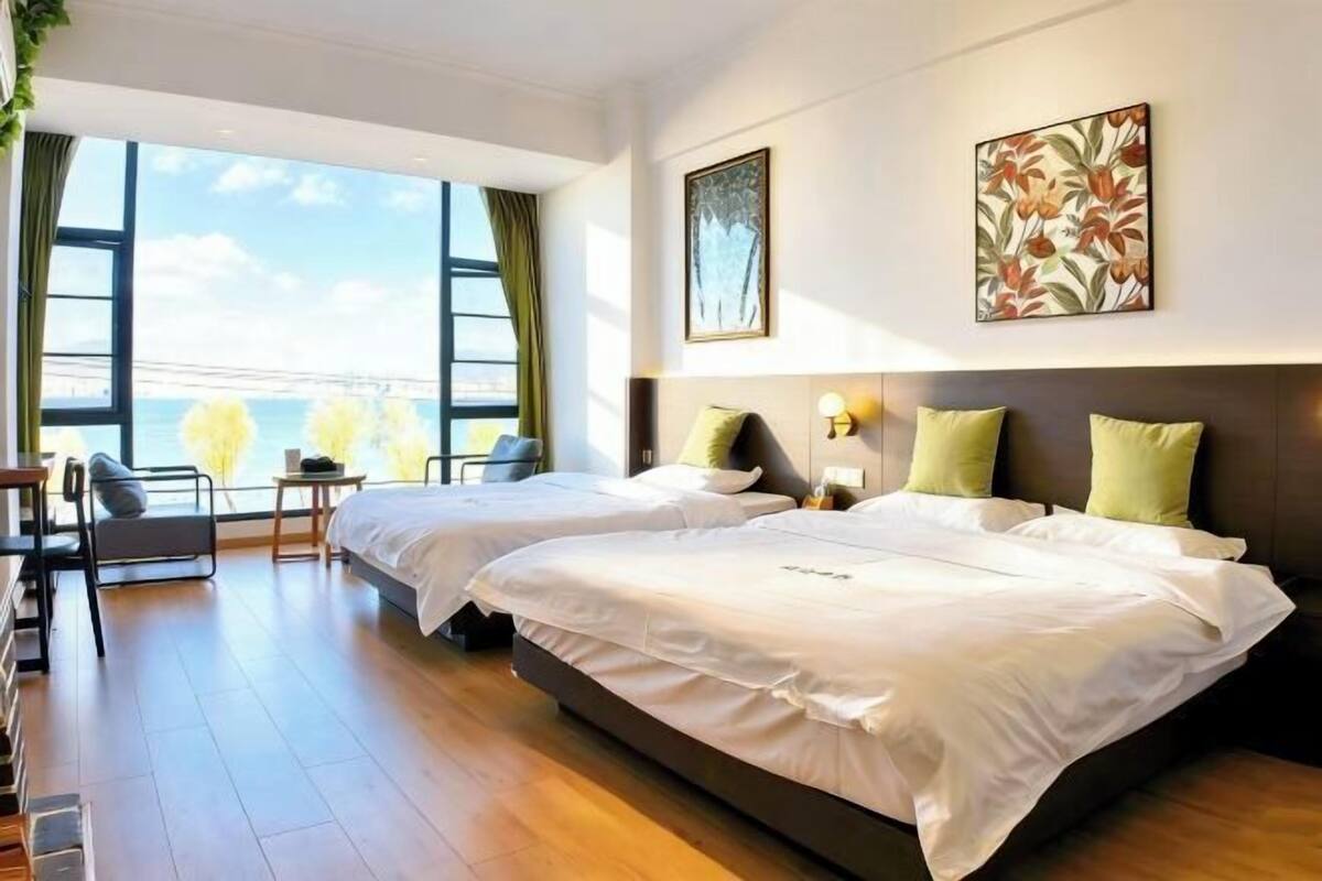 Une chambre d’hôtel avec deux lits, un bureau et une vue sur la mer.