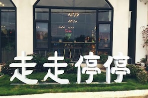 A storefront with large white Chinese characters, a glass window, and a green lawn. - Dali Zouzou Tingting Seaview Inn (Dali City)