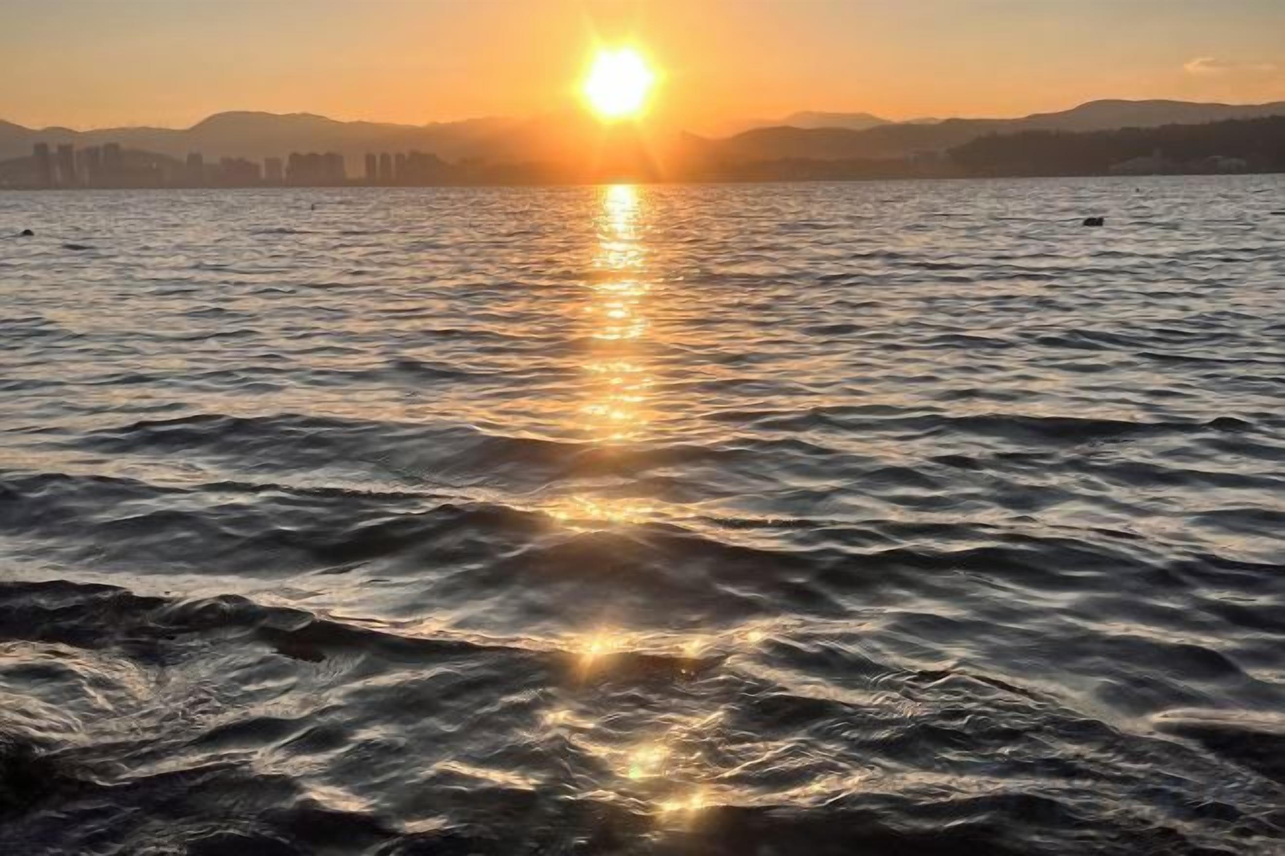 Un cuerpo de agua reflejando la luz del sol con un horizonte lejano de la ciudad.