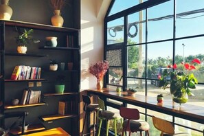 A room with a large window, a bookshelf, and a table with chairs. - Dali Zouzou Tingting Seaview Inn (Dali City)