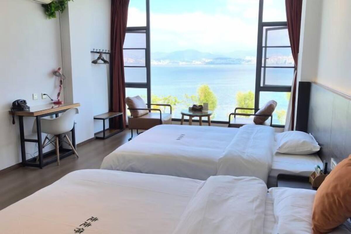 Une chambre d’hôtel avec deux lits, un bureau et une vue sur un plan d’eau.