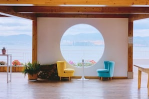 A room with a circular window, two chairs, a table, and a view of a cityscape. - Dali Zouzou Tingting Seaview Inn (Dali City)