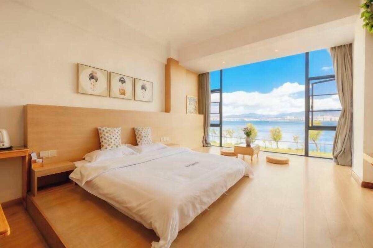 Une chambre d’hôtel moderne dotée d’un grand lit, d’une table de chevet, d’un bureau et offrant une vue sur la mer.
