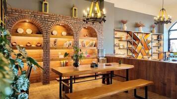 A cozy dining area with a wooden table and bench, brick shelving with decorative items, and a chandelier.
