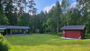 En fastighet med en stor gräsyta, ett rött förråd och ett hus med en veranda.