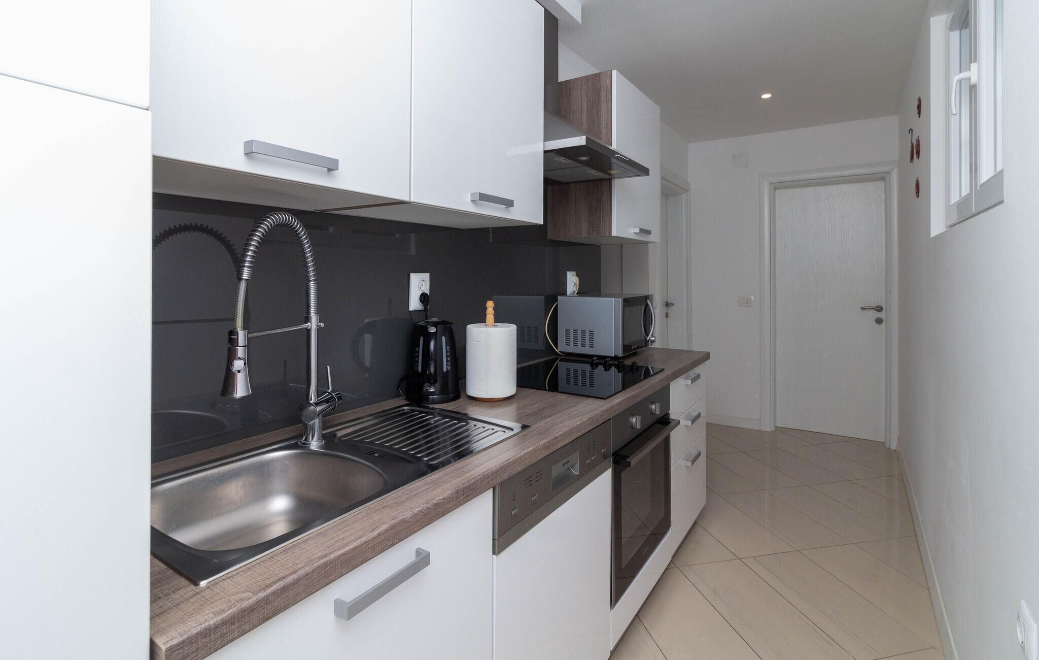 Een moderne keuken met een roestvrijstalen spoelbak, een koffiezetapparaat en een magnetron.