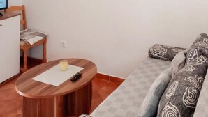 A living room with a wooden table, a sofa with patterned cushions, and a chair. - Beautiful apartment in Vir with house sea view (Vir)