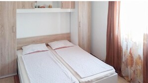 A double bed with a wooden headboard and a white mattress. There is a small shelf above the bed with decorative items. - Beautiful apartment in Vir with house sea view (Vir)