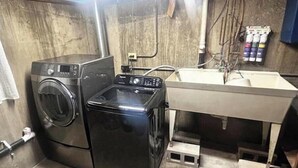A laundry area with a washing machine and dryer, a sink, and electrical outlets. - Townhome with Game Zone, Big Beds, & Smart TVs (Westmont)