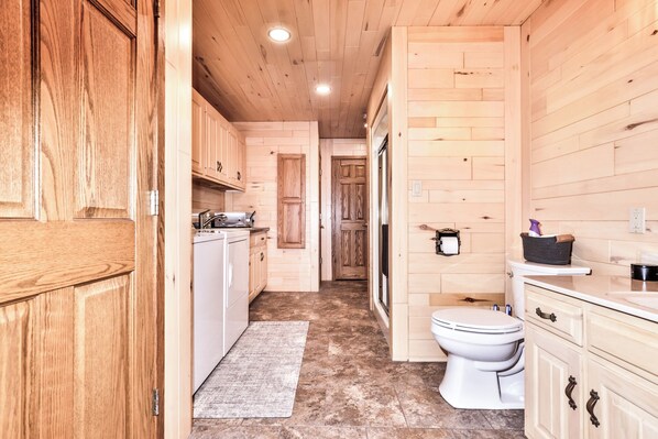 A compact, wooden-finished bathroom with a toilet, sink, and cabinets.
