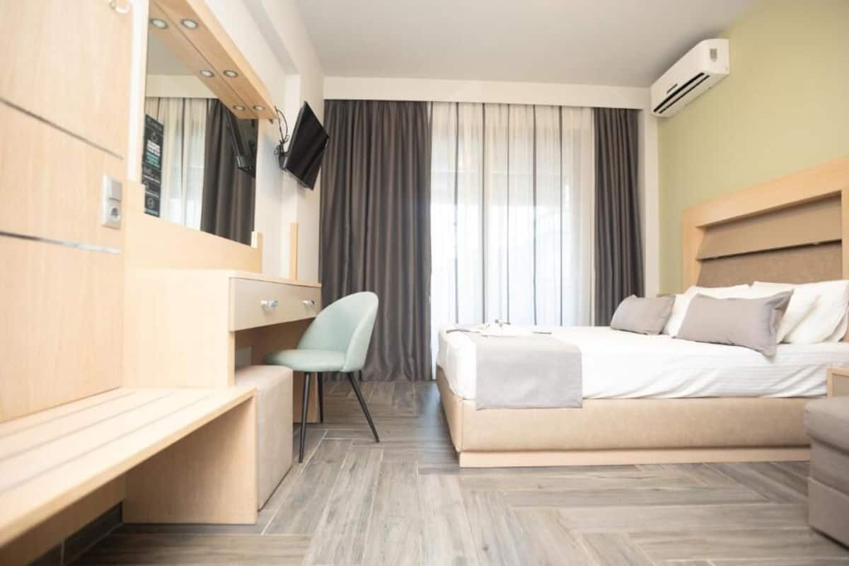 Una habitación de hotel moderna con una cama, un escritorio, una silla, un televisor y un equipo de aire acondicionado.