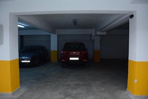A parking garage with two cars parked, one red and one blue. - Amalia Center (Volvi)