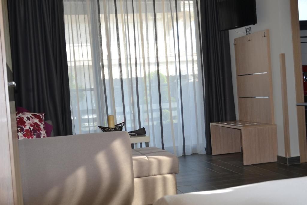 A modern hotel room with a sofa, a small table with a basket, and a kitchenette area.