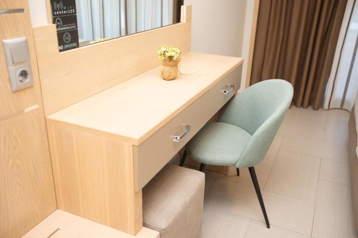A modern room with a wooden desk, a light green chair, and a small plant on the desk.