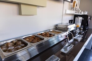 A buffet line with various food items in metal containers.