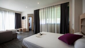 Una habitación de hotel con cama, sofá, escritorio y televisión.