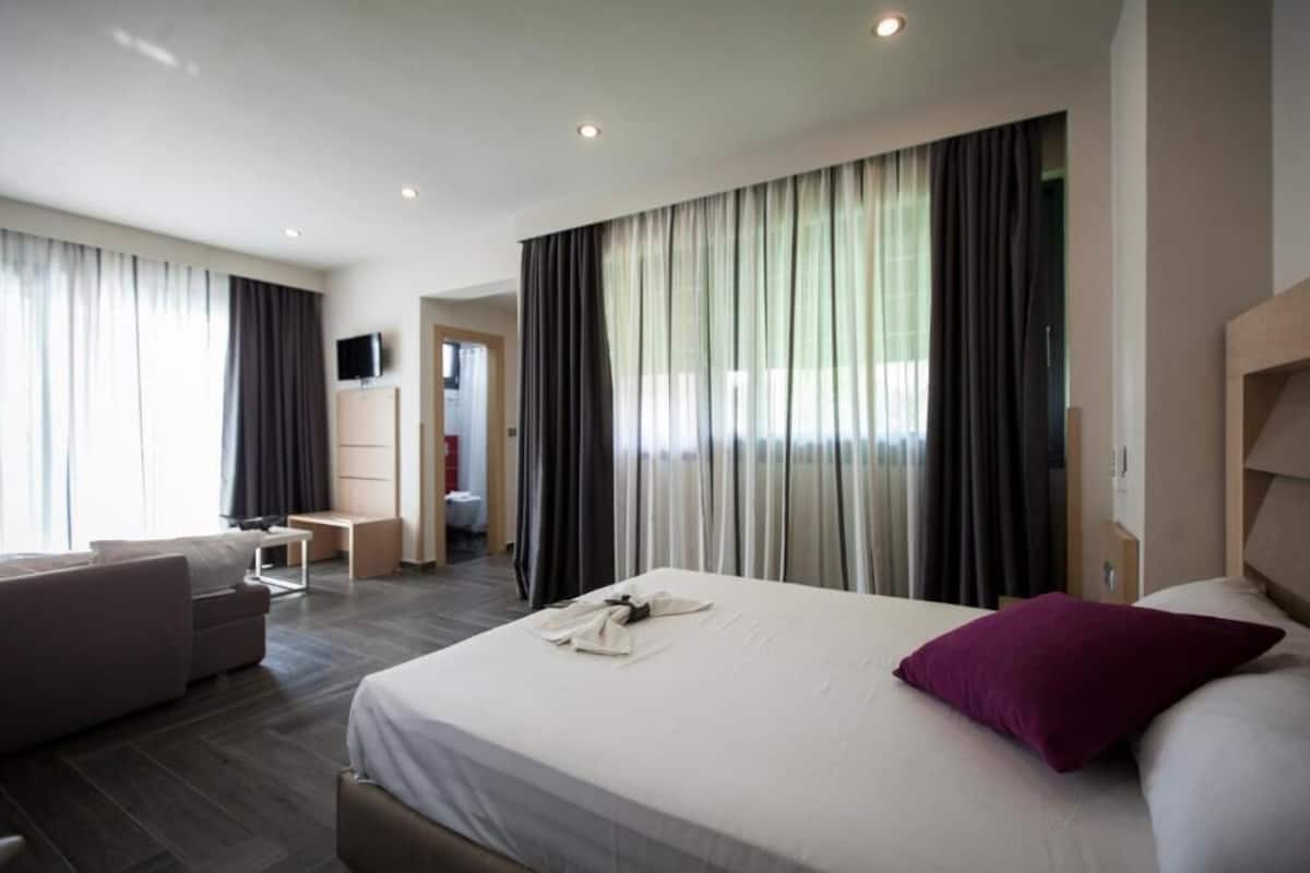 Una habitación de hotel con cama, sofá, escritorio y televisión.