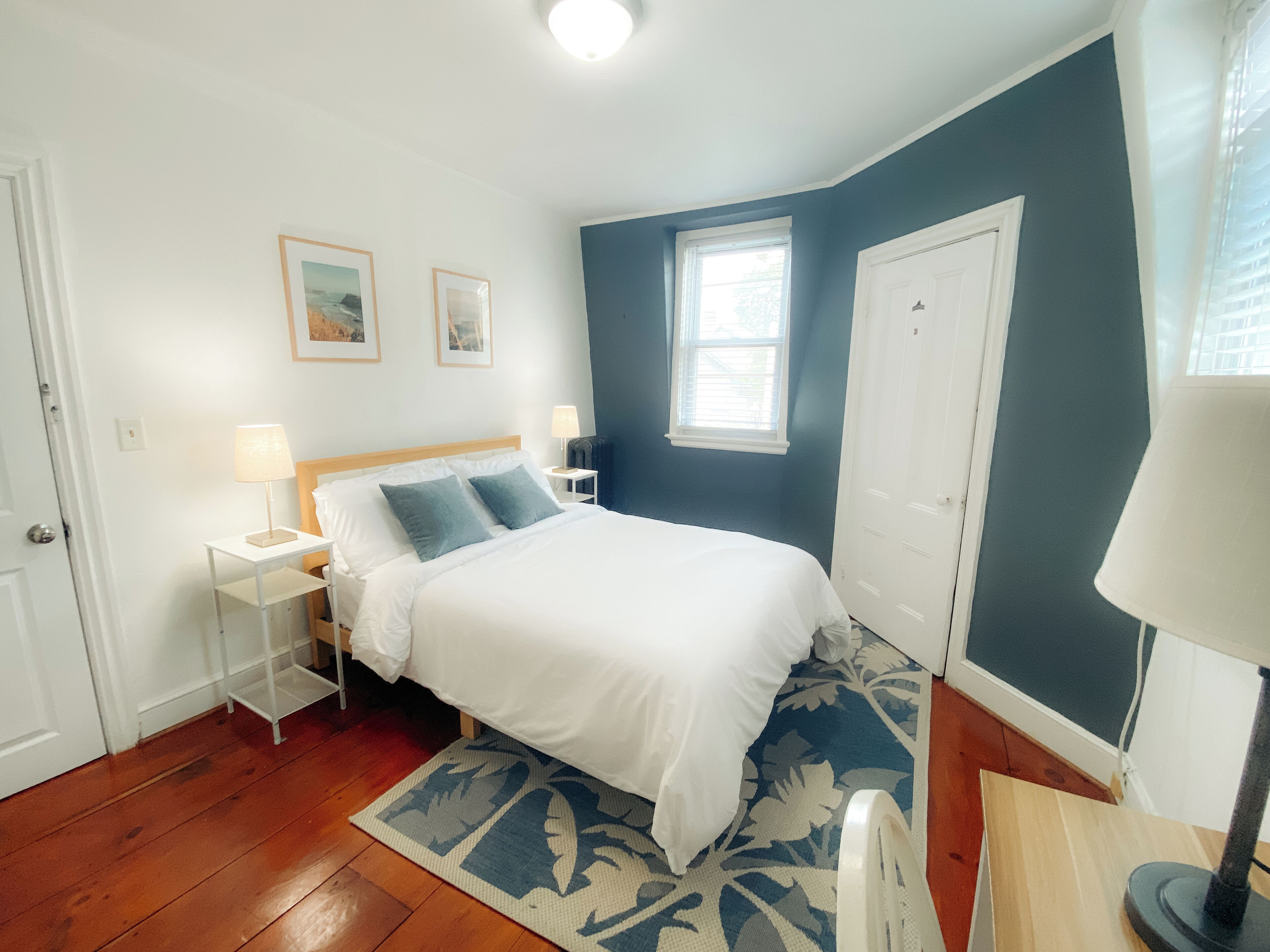 A neatly arranged bedroom with a bed, bedside tables, a window, and a door.