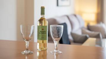 A bottle of Marqués de Cáceres wine and two glasses on a wooden table in a living room.