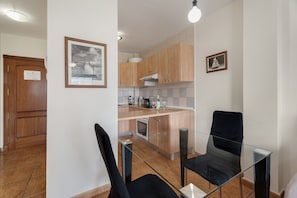 A modern kitchen with wooden cabinets, a glass dining table, and a black chair.